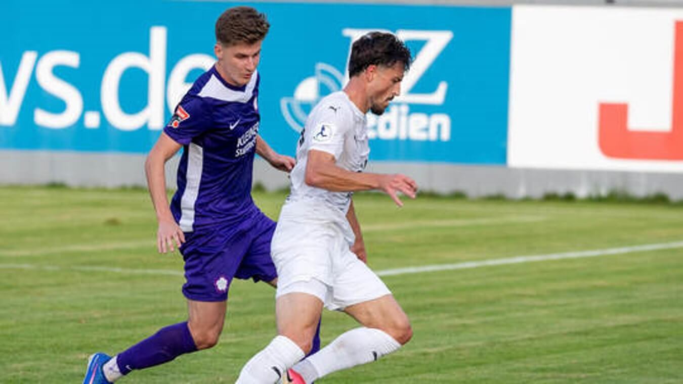 Zwei Fußballspieler kämpfen im BFV-Pokal – einer im lila Trikot, einer im weißen FCN-Trikot – auf grünem Rasen